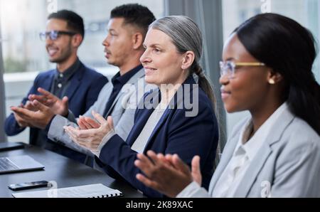 Questo discorso ha riempito la loro mente di più ispirazione, una donna d'affari matura che applaude ai suoi colleghi durante una riunione in un ufficio. Foto Stock