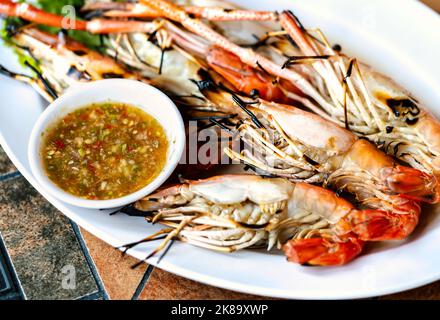 Primo piano gamberi giganti del fiume alla griglia in piatto bianco sul tavolo, primo piano immagine pesce Thailandia, gamberi giganti del fiume alla griglia con frutti di mare piccanti e acidi s Foto Stock