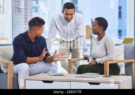 Condividere un po 'di ufficio banter. Tre uomini d'affari che hanno una conversazione in un ufficio moderno. Foto Stock