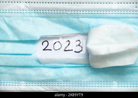 2023 scritto su carta su una maschera medica strappata, felice anno nuovo 2023, assistenza sanitaria, vacanze e medicina Foto Stock