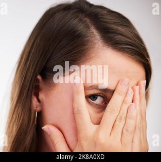 Whos peeking. Studio shot di una giovane donna che copre il suo viso con le mani su uno sfondo bianco. Foto Stock