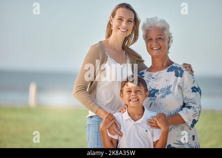 Madre, nonna e bambino felice all'aperto insieme con l'amore della famiglia e la cura nella natura. Ritratto di una donna anziana, mamma e bambino sorridono con un abbraccio Foto Stock