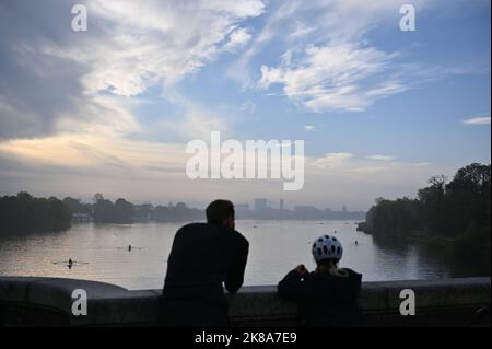 Amburgo, Germania. 22nd Ott 2022. Un uomo e un bambino guardano fuori dal ponte di Krugkoppel contro un cielo nebbioso blu al Außenalster con numerose barche a remi. Credit: Jonas Walzberg/dpa/Alamy Live News Foto Stock