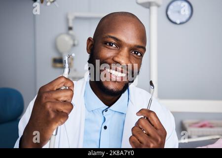 Quando ultimo avete fatto i vostri denti professionalmente puliti. Ritratto di un giovane uomo che tiene gli attrezzi di pulizia dei denti nel suo ufficio dentisti. Foto Stock