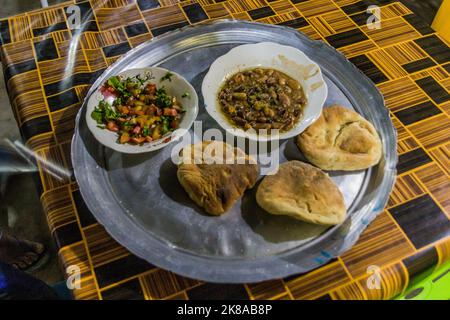 Pasto tradizionale in Sudan - fuul (stufato di fave cotte), insalata e pane. Foto Stock