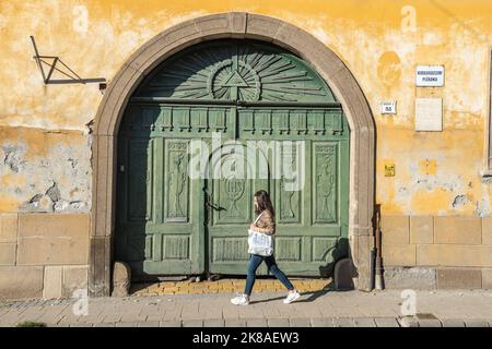 Eger, Ungheria – 17 ottobre 2022. Porta verde della chiesa parrocchiale di Kisboldogaszony a Szechenyi utca, 51 a Eger, Ungheria. Vista con una signora che cammina vicino. Foto Stock