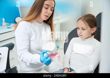 Dentista pediatrico che insegna la tecnica di spazzolatura dei denti della bambina Foto Stock