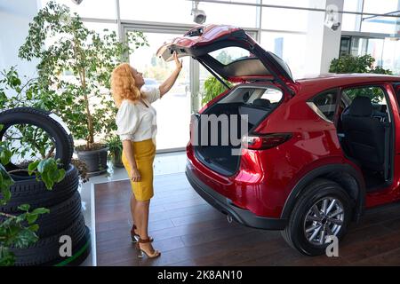 Donna che prende la decisione circa l'acquisto dell'automobile Foto Stock