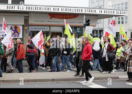 Duesseldorf, Germania. 22nd Ott 2022. Durante una dimostrazione, i partecipanti con le bandiere camminano oltre lo slogan 'maggio lo sfortunato disturbare il fortunato, nella cui felicità?', che si trova sulla tettoia di una libreria. Un'alleanza sociale ha richiesto dimostrazioni a livello nazionale, chiedendo ulteriori misure di aiuto a breve termine, un tetto massimo per i prezzi dell'elettricità e del gas, ulteriori sussidi per l'energia e la fine della dipendenza dai combustibili fossili. Credit: David Young/dpa/Alamy Live News Foto Stock