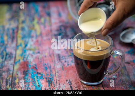 Americano con panna versata in bevanda Foto Stock