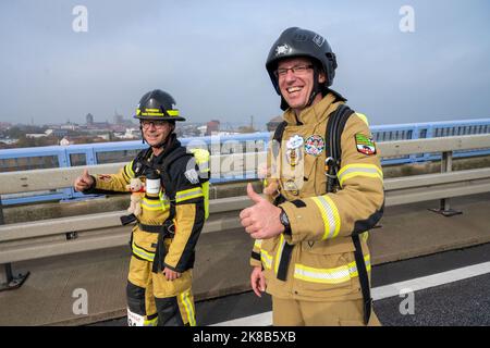 22 ottobre 2022, Meclemburgo-Pomerania occidentale, Stralsund: Steven Dreher (l-r) di Schönebeck an der Elbe e Andre Lippisch di Cobbelsdorf vicino a Wittenberg stanno iniziando come vigili del fuoco dai loro reparti di vigili del fuoco volontari. Tra le altre cose, stanno correndo per i bambini affetti da cancro, e lo stanno facendo in piena attrezzatura antincendio. Il ponte Rügen attraversa il nuovo ponte Rügen di Stralsund e Altefähr, inaugurato nel 2007. Con oltre 3500 partecipanti, la maratona di Rügenbrücken è uno dei più grandi eventi sportivi del Meclemburgo-Pomerania anteriore. Ci sono un totale di sette Foto Stock