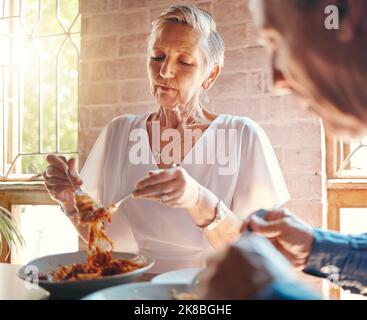 La vecchia coppia che mangia pasta insieme al ristorante in una data che celebra l'anniversario. Cibo, cena romantica e uomo e donna anziana che si gustano spaghetti Foto Stock