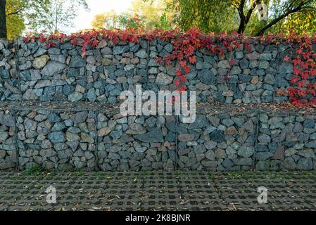 un moderno parco urbano sviluppo di oggetti ambientali, gabion recinzione parete da rete di acciaio con pietre Foto Stock