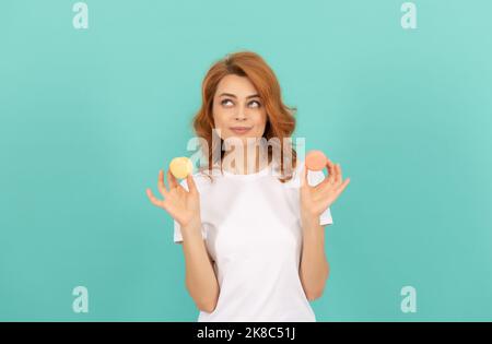 ragazza positiva tenere dolce macaron biscotto francese su sfondo blu Foto Stock