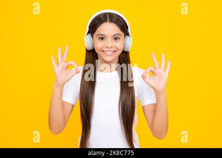 Felice ritratto adolescente. Bambini che ascoltano musica con le cuffie. Ragazza che ascolta canzoni tramite auricolari wireless. Accessorio per dispositivo auricolare. Elegante adolescente Foto Stock