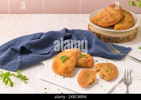 Polpettine di carne e foglie di prezzemolo su piatti di ceramica bianca in una cucina da banco. Foto Stock