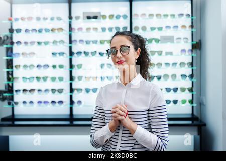 Ritratto di bella giovane donna che prova nuovi occhiali fotosensibili in negozio ottico. Foto Stock