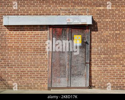 Taylor, Texas USA - muro in mattoni con vecchia porta scorrevole con cartello radioattivo per riparo in caduta Foto Stock