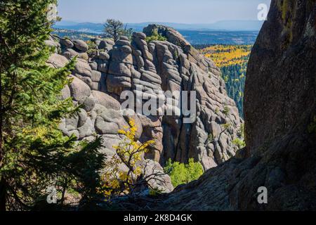 Un enorme affioramento roccioso si affaccia sulla distesa di coloratissime foglie autunnali nelle White Mountains dell'Arizona lungo l'East Baldy Trail. Foto Stock