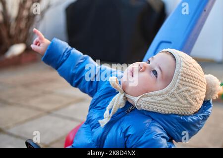 cute toddler sta guidando il suo scooter giocattolo e spingere l'automobile nel cortile posteriore Foto Stock