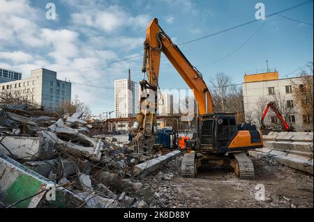 L'escavatore con forbici idrauliche taglia travi in calcestruzzo Foto Stock