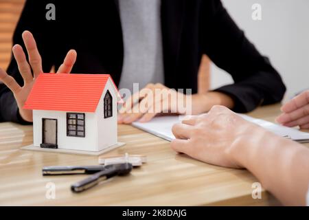 Giovane uomo cliente parlare con l'agente di contratto di acquisto casa e l'accordo di ipoteca immobiliare e spiegare per la pianificazione in casa ufficio Foto Stock