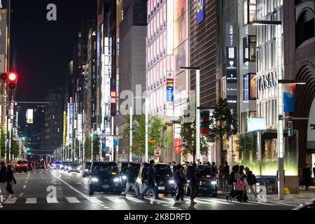 Tokyo, Giappone. 22nd Ott 2022. Scene di strada generali di notte di un importante incrocio a Ginza con attraversamento pedonale. Ginza è un popolare quartiere di shopping di lusso noto per la sua selezione di negozi al dettaglio di lusso e ricchezza simile alla Fifth Avenue. E' adiacente alla Citta' di Chiyoda, sede del Palazzo Imperiale e sede del Governo Giapponese. Il Giappone ha recentemente riaperto al turismo dopo oltre due anni di divieti di viaggio a causa della pandemia COVID-19. Lo Yen si è notevolmente deprezzato nei confronti del dollaro USA, creando turbolenze economiche per il commercio internazionale e l'economia giapponese. Turisti Foto Stock
