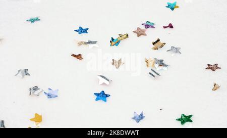 confetti. Coriandoli di stelle colorate. Coriandoli colorati e luminosi. Coriandoli multicolore di pirocista, sparsi sulla neve bianca. Primo piano. Decorazioni festive. Foto di alta qualità Foto Stock