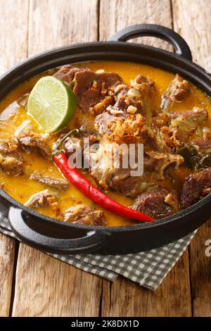 Curry di agnello o indonesiano Gulai Kambing per Eid closeup sulla padella sul tavolo di legno. Verticale Foto Stock