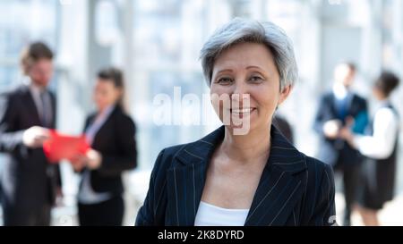 Ritratto di donna d'affari asiatica matura in carica con le braccia incrociate e sorridenti. Dirigente asiatico femminile che guarda la fotocamera con sicurezza. Foto Stock