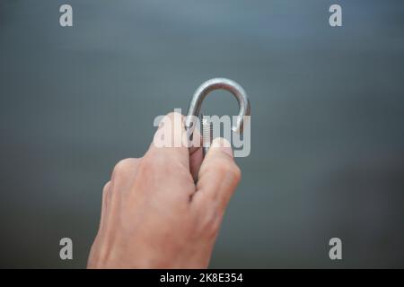 Carbina in mano. Blocco per il fissaggio. Gancio di sicurezza. Attrezzatura di salvataggio. Oggetto in acciaio. Foto Stock