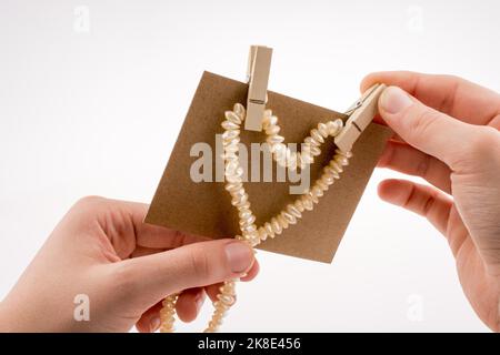 Collana di perle costituisce forma di cuore su carta su sfondo bianco Foto Stock