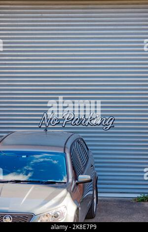 Nessun cartello di parcheggio dipinto su una porta a rulli con auto parcheggiata direttamente di fronte. Foto Stock