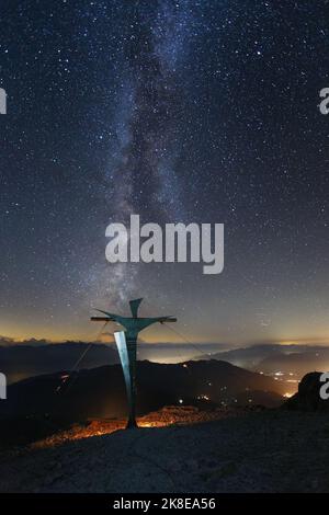 Paesaggio notturno con cielo stellato, via lattea. Croce sommitale della vetta del monte Hochkönig. Austria. Alpi Orientali. Europa. Foto Stock