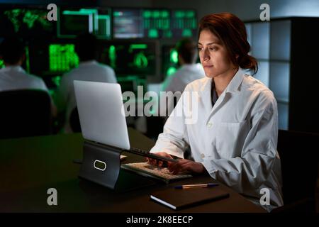 Ricercatore medico che scrive sul suo computer da tavolo in un laboratorio di ricerca biologica applicata Scienza. Tecnici di laboratorio nella condotta dei camici bianchi Foto Stock