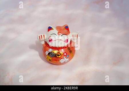 Gatto giapponese (maneki neko) in porcellana. Un neko di maneki è un simbolo tradizionale di buona fortuna e fortuna. Foto Stock