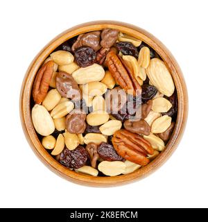 Miscela di noci e frutti di bosco, con cioccolato al latte, in una ciotola di legno. Snack dolci di noci pecan arrosto, mandorle, arachidi, mirtilli rossi secchi e cioccolato. Foto Stock