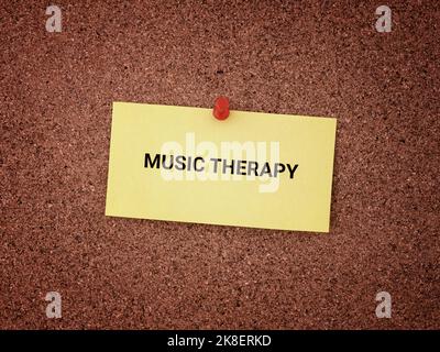 Una nota di carta gialla con le parole Music Therapy su di essa fissata ad una tavola di sughero. Primo piano. Foto Stock