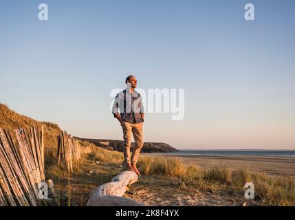 Uomo con le mani in tasca in piedi sul log Foto Stock