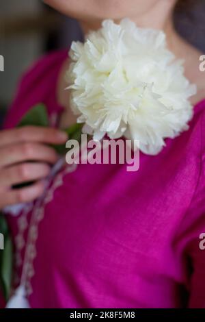Donna con vestito rosa Vyshyvanka che tiene fiore di peonia bianca Foto Stock