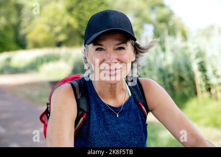 Donna anziana sorridente che indossa il cappuccio Foto Stock