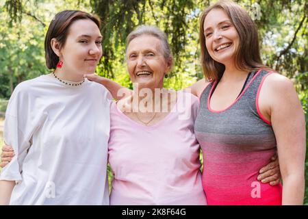 Donna anziana felice con figlia e nipote in piedi al parco Foto Stock