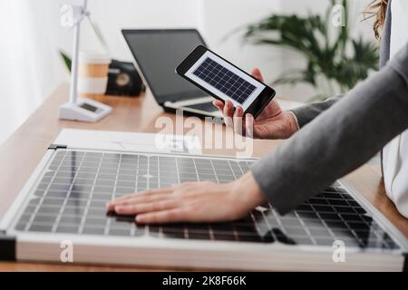 Donna d'affari carica cellulare con modulo solare portatile, primo piano Foto Stock