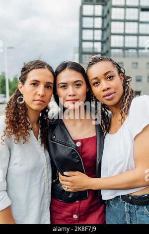 Giovani amici multirazziali con le braccia intorno Foto Stock