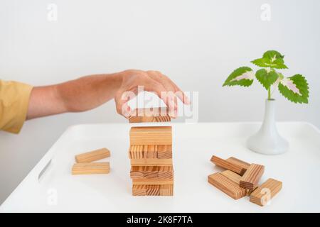 Mano dell'uomo che accatastano i blocchi di legno sul tavolino da caffè Foto Stock