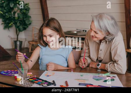 Nonna aiutare nonna nella pittura a casa Foto Stock