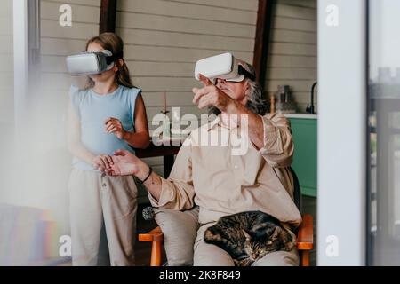 Nonno e nipote indossano occhiali VR a casa Foto Stock