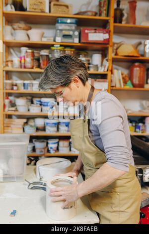 Vasaio maturo con ceramica che lavora in officina Foto Stock