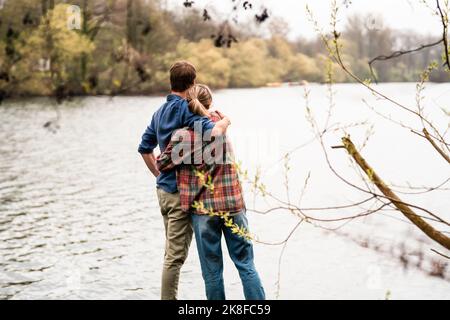 Coppia abbracciandosi guardando il lago Foto Stock