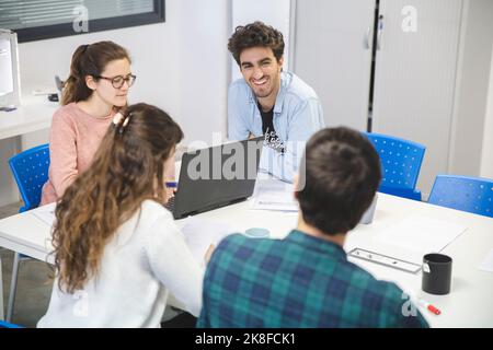 Uomo d'affari sorridente che parla con colleghi multirazziali in ufficio Foto Stock